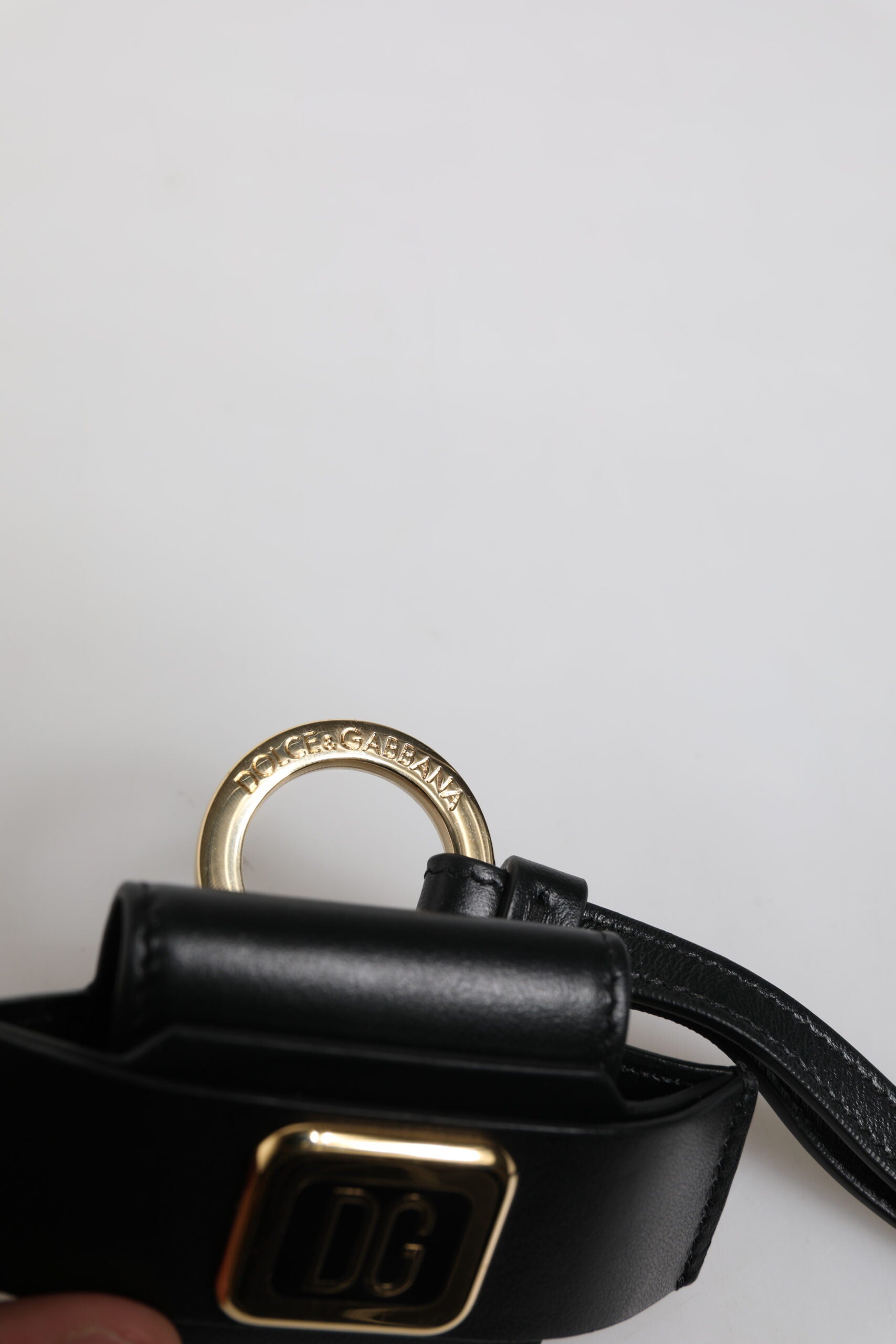 حافظة سماعات Airpods من دولتشي آند غابانا، بحزام جلدي أسود، ولوحة معدنية ذهبية بشعار دولتشي آند غابانا