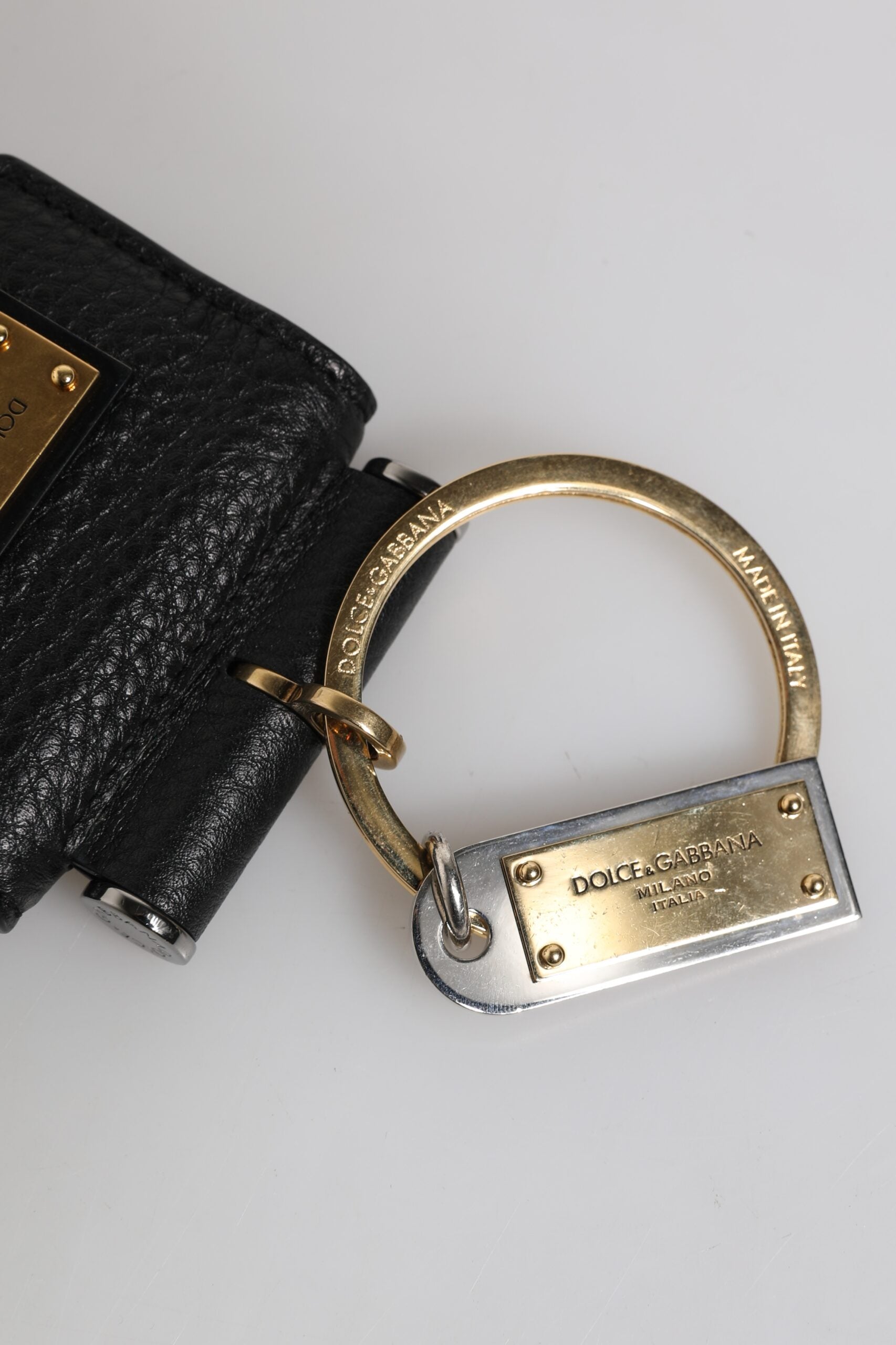 حافظة سماعات Airpods من دولتشي آند غابانا، بحزام جلدي أسود، ولوحة معدنية ذهبية بشعار دولتشي آند غابانا