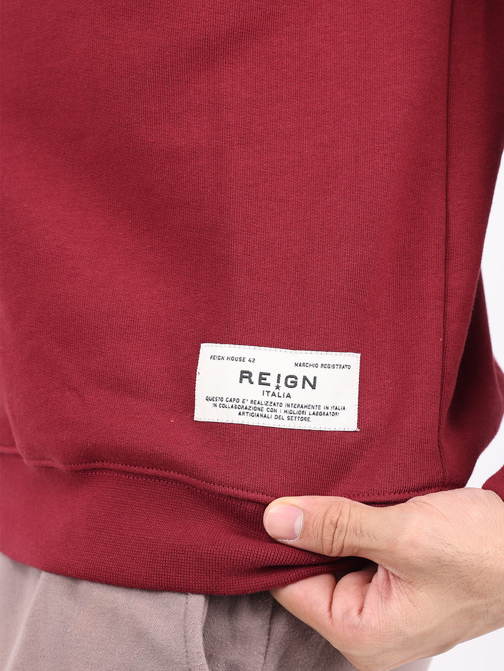 Close-up of Reign Italia logo patch on burgundy sweatshirt